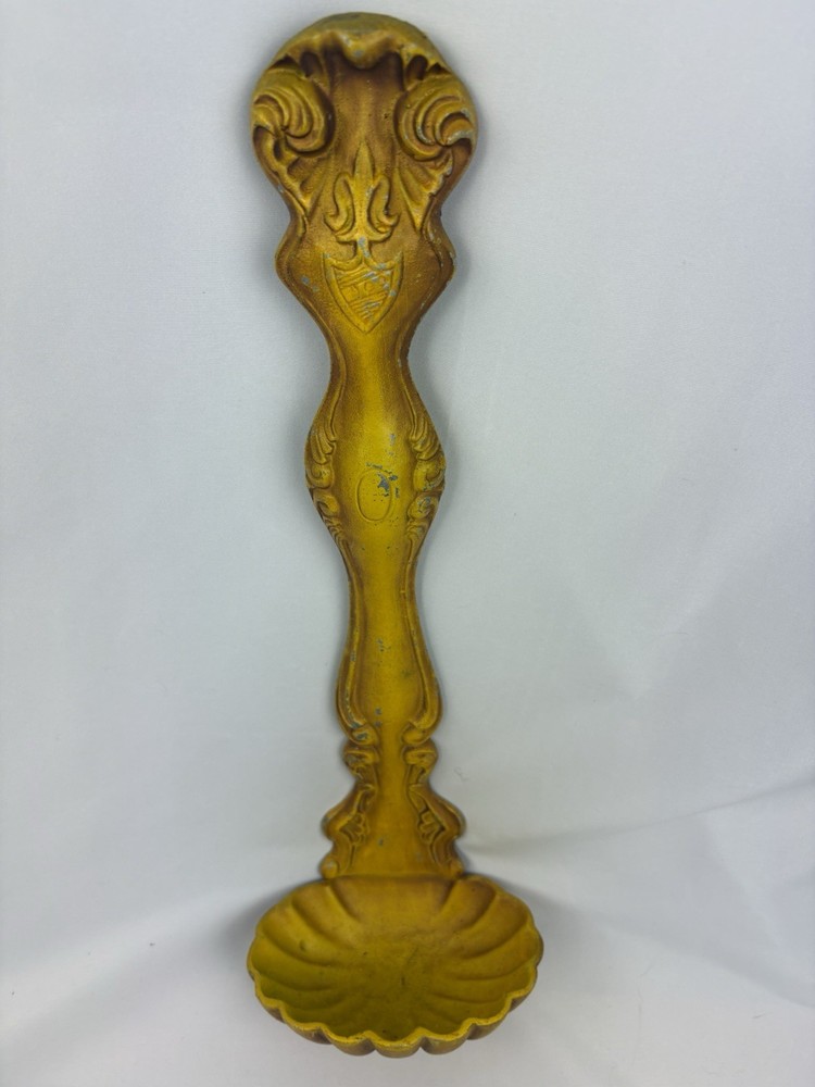 Vintage cast metal ladle-shaped wall hanging with ornate handle and scalloped