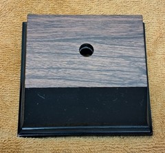 Trophy base, black plastic, woodgrain top, 3 7/6″W x 3 1/8″L x 1 1/4″H, #F.P.35