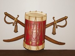 VINTAGE 20″ WIDE 12″ HIGH SEXTON METAL DRUM & SWORDS WALL HANG PLAQUE